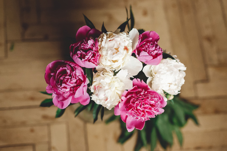 Beautiful pink and white peonies bouquet in glass jar on rustic wooden floor , flat lay. Floral decor and arrangement. Gathering flowers. Rural still life, countryside flowersの写真素材