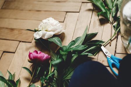 Beautiful pink and white peonies on rustic wooden floor with old glass jar and scissors. Copy space. Floral decor and arrangement. Gathering flowers. Rural still life, countryside flowersの写真素材