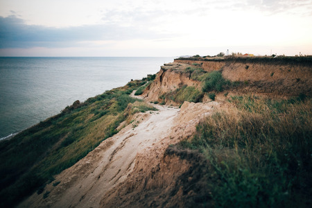 Beautiful sandy cliff  and calm sea surface, pink sky at sunset light. Beach  on tropical island at ocean bay or lagoon. Tranquil calm moment. Summer vacation. Copy spaceの写真素材
