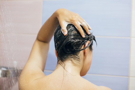 Young happy woman washing her hair with shampoo, foaming with hands. Beautiful  brunette girl taking shower and enjoying relax time. Body, hair and skin hygiene, lifestyle concept.の写真素材