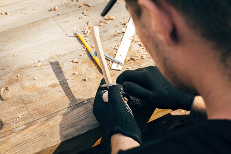 Hands carving spoon from wood, working with chisel close up. Process of making wooden spoon, chisel and shavings on dirty table. Wooden workshop. Handmade festival in summer parkの写真素材