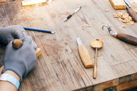 Wooden workshop. Hands carving spoon from wood, working with chisel close up. Process of making...
