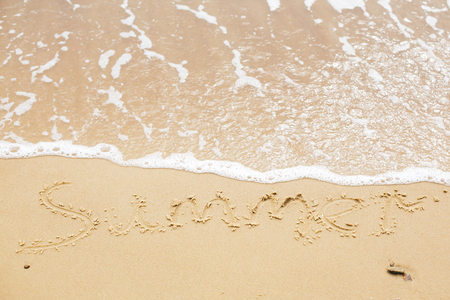 Summer sign on beach. Written summer text word on sandy beach  and sea waves with foam. Hello summer concept. Top view. Vacation, relax and travel. Copy spaceの写真素材