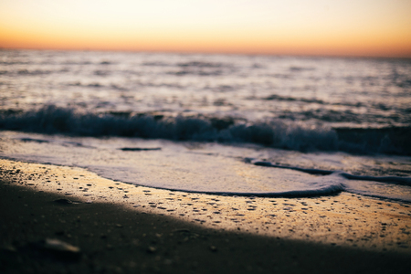Beautiful sea waves foam closeup and sandy beach with seashells in sunrise light on tropical island. Waves in ocean at sunset. Tranquil calm moment. Summer vacation. Copy spaceの写真素材