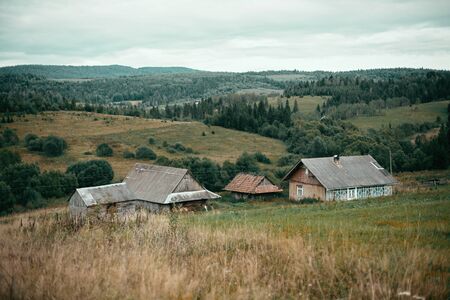 Beautiful old wooden houses on hills and sunny meadow in mountains. Rural simple life in...