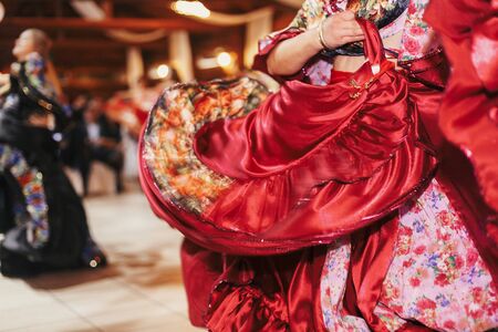 Gypsy dance festival, Woman performing romany dance and folk songs in national clothing. Beautiful roma gypsy girls dancing in traditional floral dress at wedding reception in restaurantの写真素材