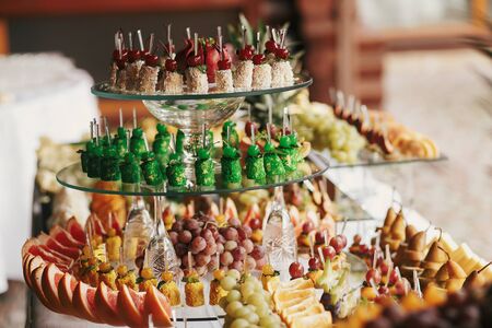 Delicious fruits appetizers, desserts on stand, modern sweet table at wedding or baby shower. Luxury catering concept. Fruit bar at wedding reception, orange,grapes,pear slicesの写真素材