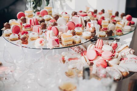 Pink and white desserts,macarons and cupcakes on stand, modern sweet table at wedding or baby...