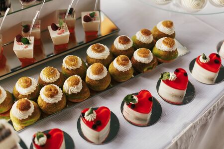 White and chocolate desserts with fruits and crem,  cupcakes on stand, modern sweet table at wedding or baby shower. Luxury catering concept. Delicious candy bar at wedding reception.の写真素材