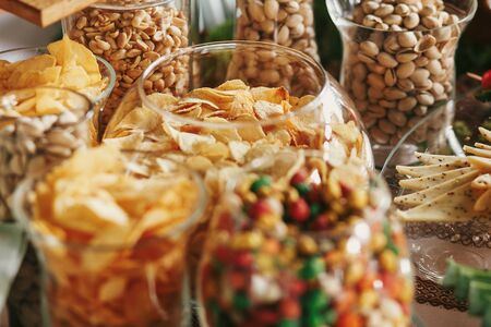 Delicious beer appetizers table at wedding reception. Chips, salty nuts, pistachio, cheese snacks on table at wedding or christmas feast. Luxury catering concept. Beer barの写真素材