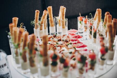 Tomatoes, basil,cheese,prosciutto, greenery and bread appetizers on table at wedding or christmas...