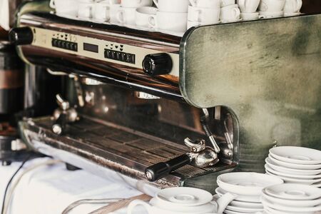 Professional coffee machine in cafe. Big steel and white coffee machine and ceramic cups and plates on table in cafe or wedding reception. Luxury cateringの写真素材