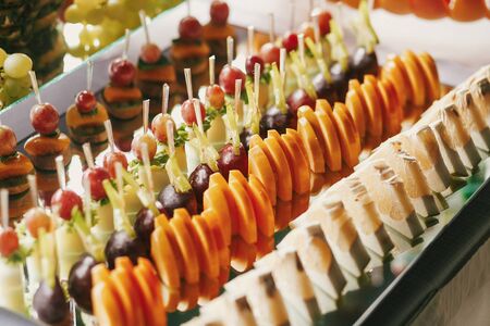 Delicious fruits appetizers, desserts on stand, modern sweet table at wedding or baby shower. Luxury...