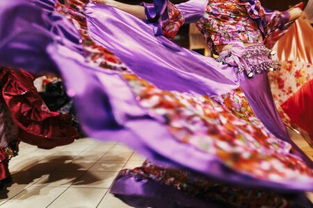 Beautiful gypsy girls dancing in traditional purple floral dress at wedding reception in restaurant. Woman performing romany dance and folk songs in national clothing. Roma gypsy festivalの写真素材