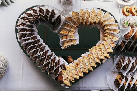 Chocolate desserts with cream in heart shape, cakes slices on stand, modern sweet table at wedding...