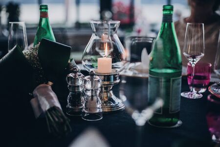 Wedding table with candles, cutlery and plates, champagne drink and glasses at reception outdoors in the evening. Luxury catering at  celebration in soft candle light. Christmas feastの写真素材