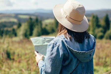 Wanderlust and travel concept. Stylish hipster girl holding map and compass, traveling in sunny...