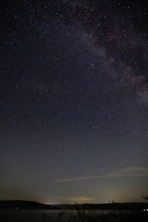 Amazing starry night sky above lake in mountains. Beautiful night sky with Milky Way and falling stars. Breathtaking landscape. View on sky from camp tentの写真素材