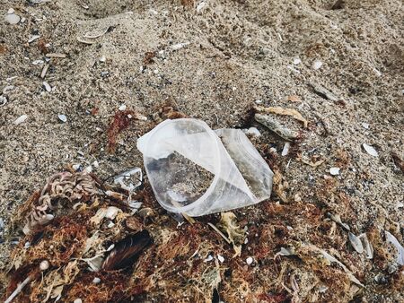 Single use plastic cup in sand, marine trash on the beach.Plastic pollution on the beach.  Stop...