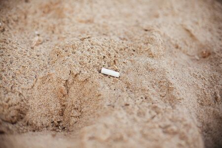 Cigarette butt in sand, marine trash on the beach. Plastic pollution on the beach.  Stop plastic...