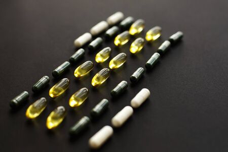 Omega 3, spirulina, chlorophyll,magnesium capsules on black dark background. Dietary supplements....