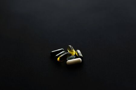 Dietary supplements. Omega 3, spirulina, chlorophyll,magnesium  capsules on black dark background. Morning vitamin pills. Health support and treatment.の写真素材