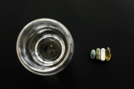 Omega 3, spirulina, chlorophyll, magnesium capsules on spoon on black dark background,flat lay....