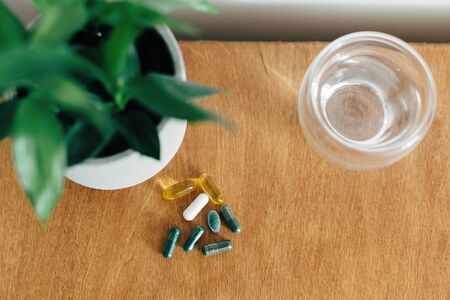 Dietary supplements. Omega 3, spirulina, chlorophyll,magnesium  capsules and glass of water on...
