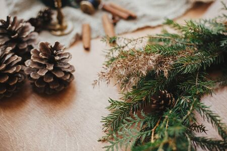 Rustic Christmas wreath detail closeup. Fir branches, pine cones, thread, berries, cinnamon on wooden table. Authentic stylish still life. Making Christmas wreath.の写真素材