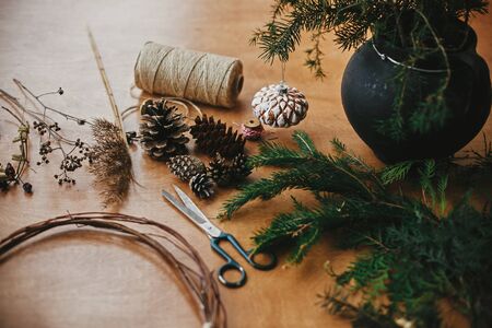 Making christmas wreath.Fir branches, pine cones, thread, scissors, wooden circle, berries and herbs for rustic wreath on wooden table. Details for workshop of making christmas wreathの写真素材