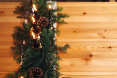 Stylish rustic christmas arrangement for festive dinner. Fir branches with pine cones and vintage candlestick with black candles on wooden table. Copy space. Christmas rural table decorの写真素材