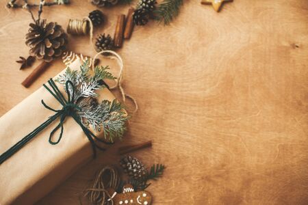 Stylish rustic christmas gifts box with cedar branch on  rural wooden table with pine conesの写真素材