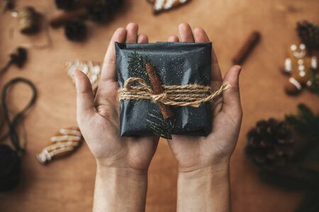 Hands wrapping christmas gift in stylish striped paper and pine branchesの写真素材
