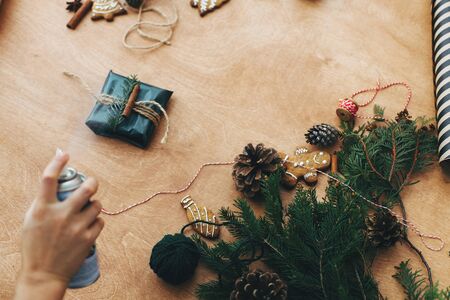 Hands wrapping christmas gift in stylish striped paper and pine branchesの写真素材
