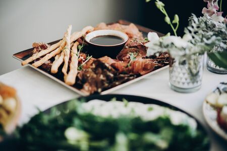 Smoked meat,sauce,prosciutto, salad appetizers on table at wedding or christmas feast. Luxury catering concept. Delicious italian food table at wedding reception.の写真素材