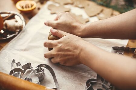 Making christmas gingerbread cookies. Hands kneading raw dough on background of rolling pin,metal cutters, anise, ginger, cinnamon, pine cones, fir branches on rustic table.の写真素材