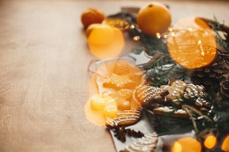 Festive gingerbread cookies with anise, cinnamon, pine cones, cedar branches and golden lights bokeh on rustic table. Space for text. Atmospheric image. Merry Christmasの写真素材