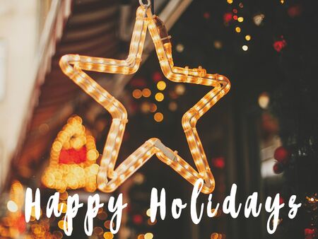 Happy Holidays  text sign on stylish christmas golden star illumination and fir branches with red and gold baubles, golden lights bokeh. Seasons greeting cardの写真素材