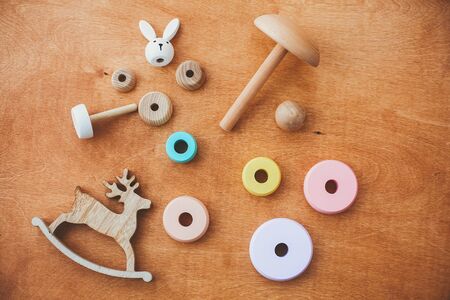Stylish wooden toys for child on wooden table. Modern colorful wooden pyramid with disassembled rings and simple bunny. Eco friendly, plastic free educational toys for toddlerの写真素材