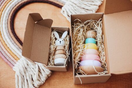 Stylish wooden toys for child in craft box on wooden table. Modern colorful wooden pyramid with...