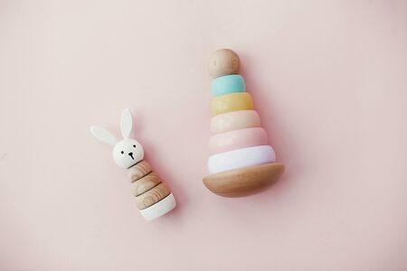 Eco friendly plastic free toys for toddler. Stylish wooden toys for child on pink background, flat lay. Modern colorful wooden pyramid with rings and wooden bunny.の写真素材
