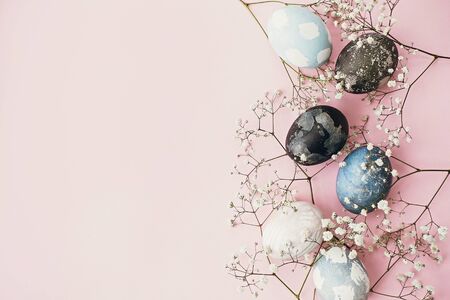 Happy Easter composition. Stylish easter eggs and spring flowers border on pink paper flat lay,...