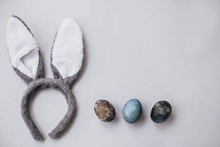 Stylish easter eggs and bunny ears flat lay on gray wallpaper with copy space. Natural dyed marble easter eggs and grey rabbit ears. Seasons greetingsの写真素材