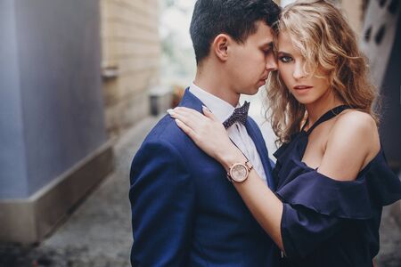 Stylish couple embracing in european city street. Sensual passionate moment. Fashionable man and woman in love gently hugging. Valentines dayの写真素材