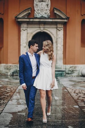 Stylish couple embracing together in european city street on background of old architecture. Fashionable man and woman in love enjoying day in city. Traveling together in Europeの写真素材