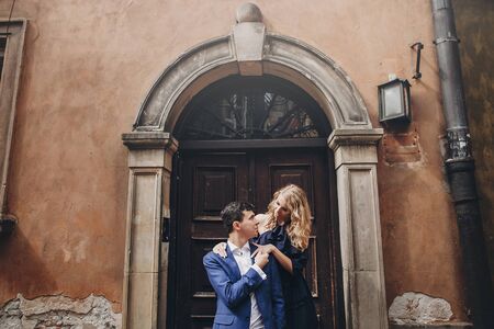 Stylish couple embracing in european city street. Sensual passionate moment. Fashionable man and woman in love gently hugging. Valentines dayの写真素材