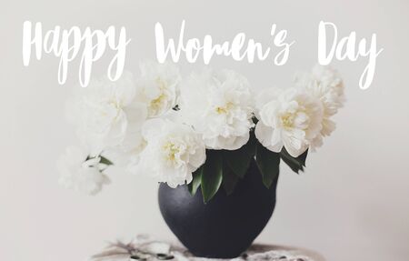 Happy Women's day text handwritten on stylish peony bouquet in black clay vase on linen fabric with scissors on rustic background. White peonies rural still life. 8 Marchの写真素材