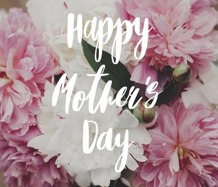 Happy Mother's Day text on peonies. Greeting card. Beautiful peony bouquet in sunny light. Stylish pink  and white peoniesの写真素材