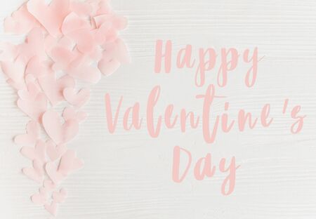 Happy Valentines day text handwritten on pink hearts. Greeting card. Valentine day concept. Pink paper heart cutouts on white background. Love. Calligraphy letteringの写真素材