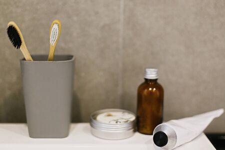 Bamboo toothbrush, ubtan for skin, solid shampoo in metal can, toothpaste in metal tube on white...